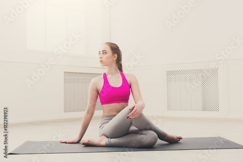 Woman training yoga in twisting sage pose.