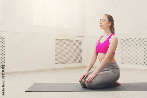 Woman training yoga in hero pose.