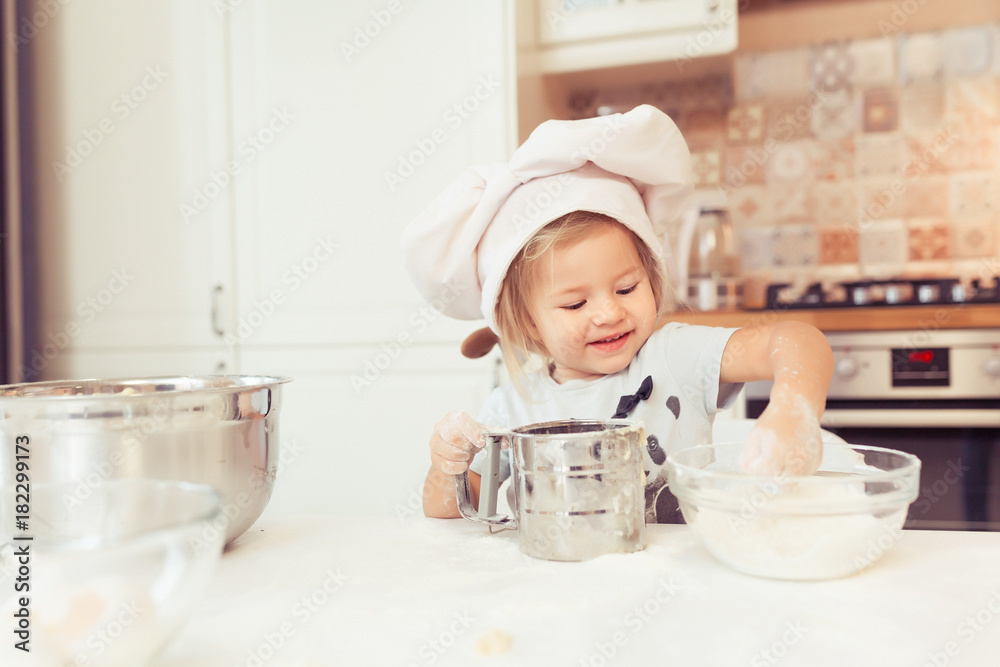 Cute little baby girl 2 years old cook apple pie for dinner. Kid prepares the dough at home in the kitchen. Healthy food at home. Cute little baby girl 2 years old cook apple pie for dinner. Kid prepares the dough at home in the kitchen. Healthy food at home.