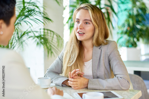Foto Portrait of two modern young women discussing work sitting at table in cafe duri