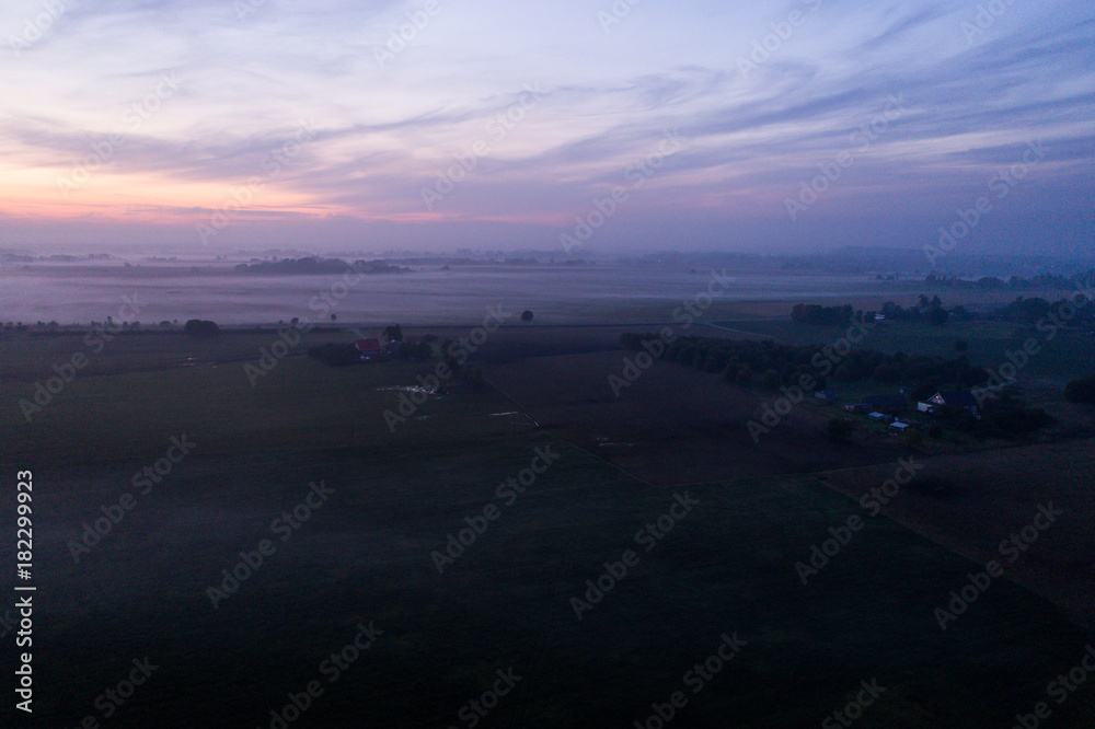 Aerial view of fields with fog at amazing sunset. Summer nature landscape