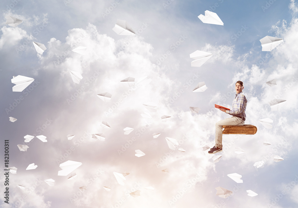 Handsome man student reading book and paper planes flying around Handsome man student reading book and paper planes flying around