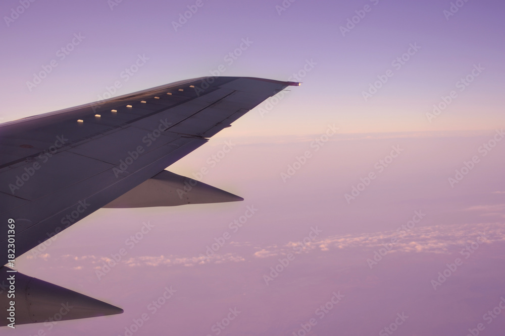 Wing of an airplane flying above the morning clouds Wing of an airplane flying above the morning clouds