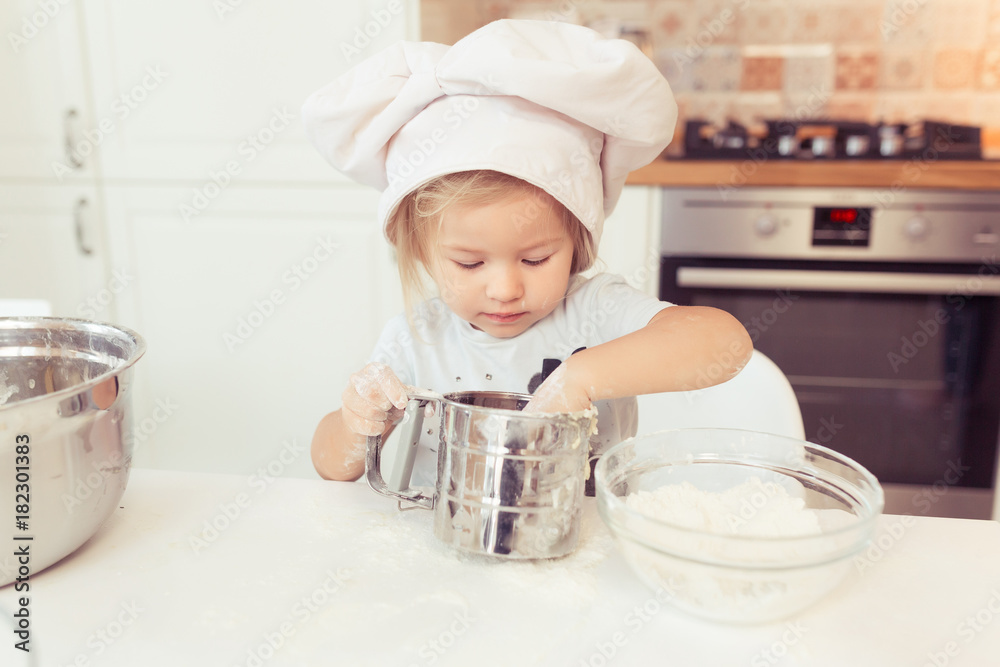Cute little baby girl 2 years old cook apple pie for dinner. Kid prepares the dough at home in the kitchen. Healthy food at home. Cute little baby girl 2 years old cook apple pie for dinner. Kid prepares the dough at home in the kitchen. Healthy food at home.