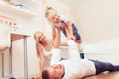 Cheerful young girl having fun with father at children room at home. Parents spending time with their baby daughter