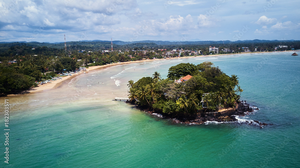 hotel island in ocean bay in front of beach aerial shot