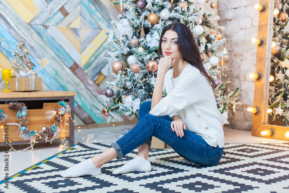 Fototapeta premium Christmas. Beautiful smiling girl. is sitting over christmas tree lights background. happy new year.