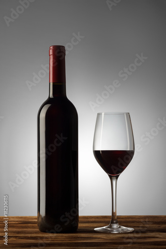 Bottle and glass of red wine with a light gradient on the background