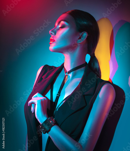 Portrait of sexy young woman in black clothes,  fashion accessories, bright makeup in neon light