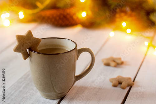 Photos Cocoa or hot chocolate with cinnamon and gingerbread on a background with spruce branches, cones and garland