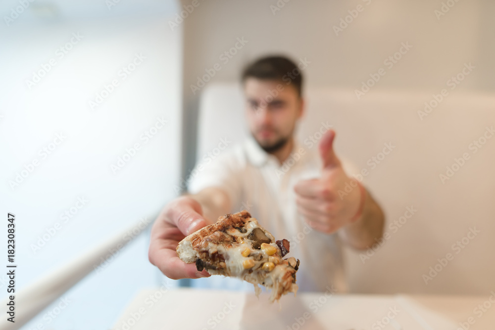 A man holds a piece of pizza in his hands and shows his finger in the entrance. A man likes pizza. Like. A man holds a piece of pizza in his hands and shows his finger in the entrance. A man likes pizza. Like.