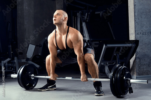 Muscular men lifting deadlift In the gym