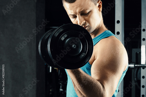 athletic man pumping up muscles with dumbbells