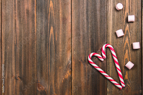 Christmas candy canes in the shape of a heart on a brown wooden table. Copy space.