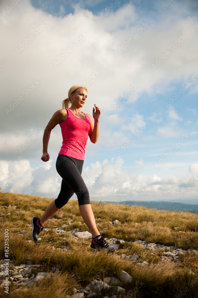 Fototapeta runner - woman runs cros country on a path in early autumn