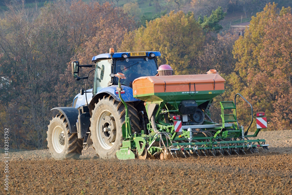 A modern tractor with a sowing machine when planting crops in a rural field  Stock Photo