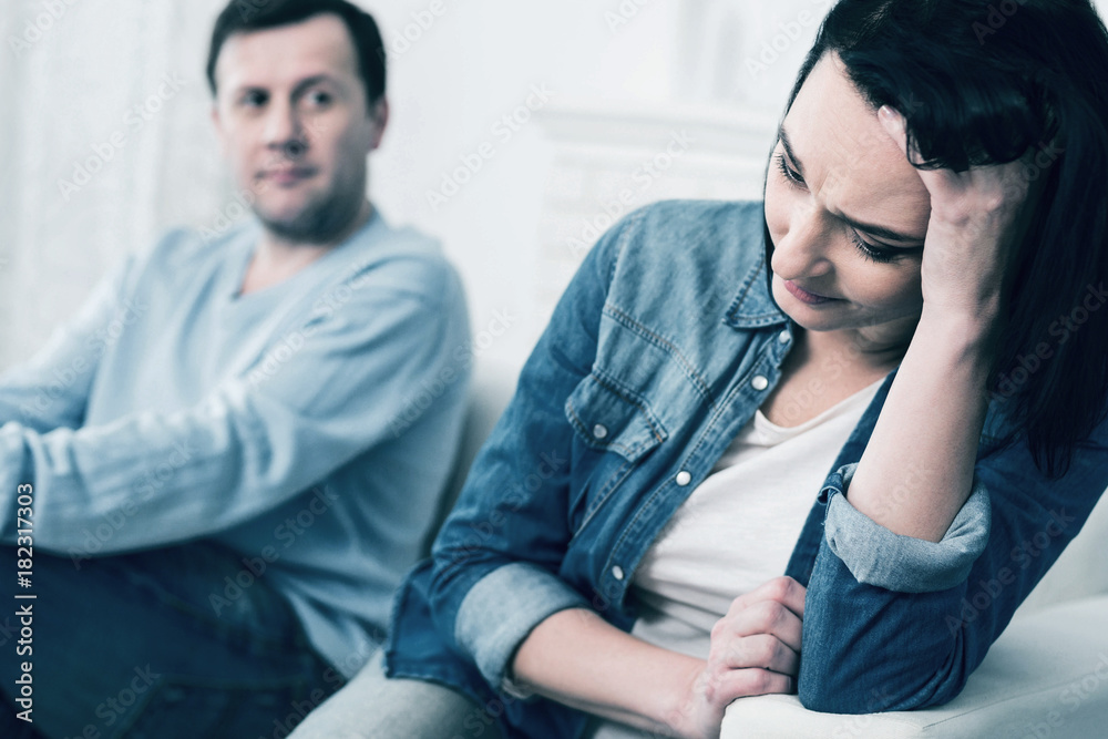 Obraz premium Family problems. Depressed woman bowing head while leaning on chair and thinking about future