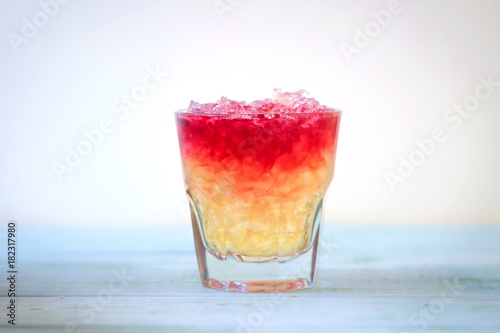 Tableau sur toile red cocktail with small ice in a glass on wooden blue background