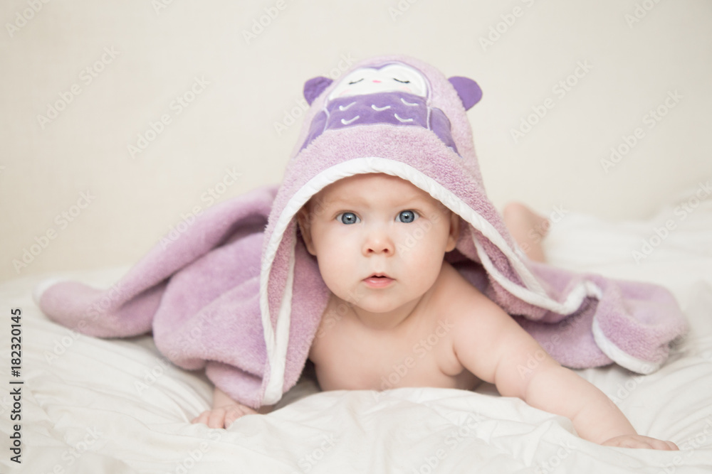 Beautiful smiling cute baby girl after a bath under the towel on the bed in the room at home. Happy child smiling Beautiful smiling cute baby girl after a bath under the towel on the bed in the room at home. Happy child smiling