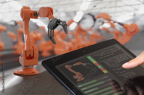 Programmer is controlling robotic arms with tablet. Automation and Industry 4.0 concept. photo