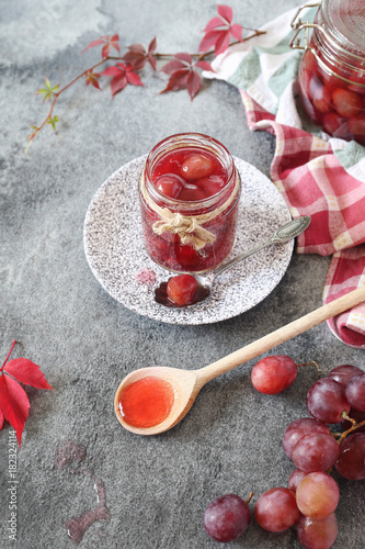Red grapes jam in jar, berry and autumn leaves