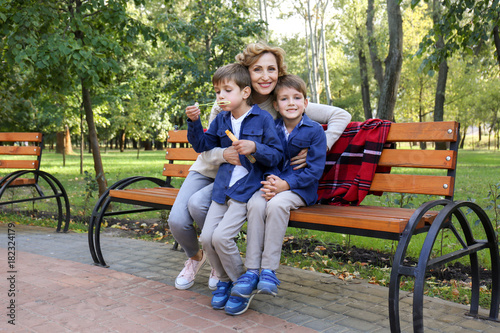 Cute little boys with grandmother in park on sunny day