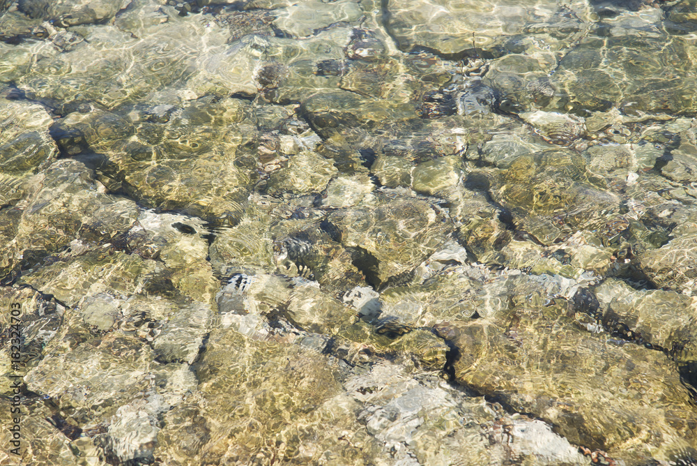 stony pattern under water blurred by the motion of the clear water