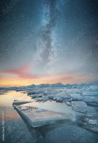 Frozen sea and night sky with stars. Beautiful natural seascape in the winter time