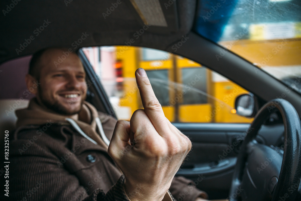 Young positive driver man in car smiling and showing sign middle finger in  traffic jam Stock Photo | Adobe Stock