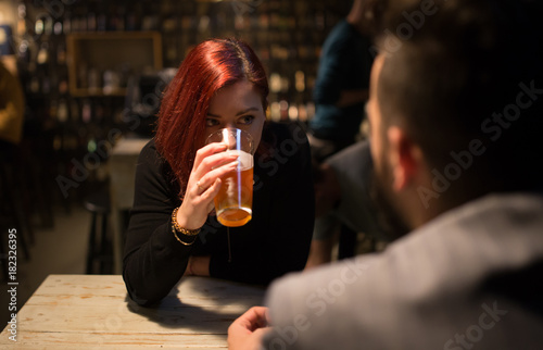 Girl in a pub, drinking beer and listening his friend