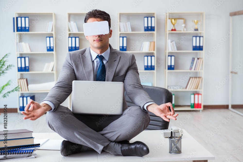 Businessman in virtual reality VR glasses meditating at desk top Businessman in virtual reality VR glasses meditating at desk top
