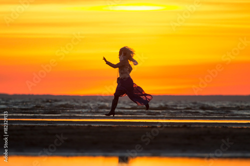 beautiful girl in a dress runs along the seashore against the sunset background run at sunset on the beach  