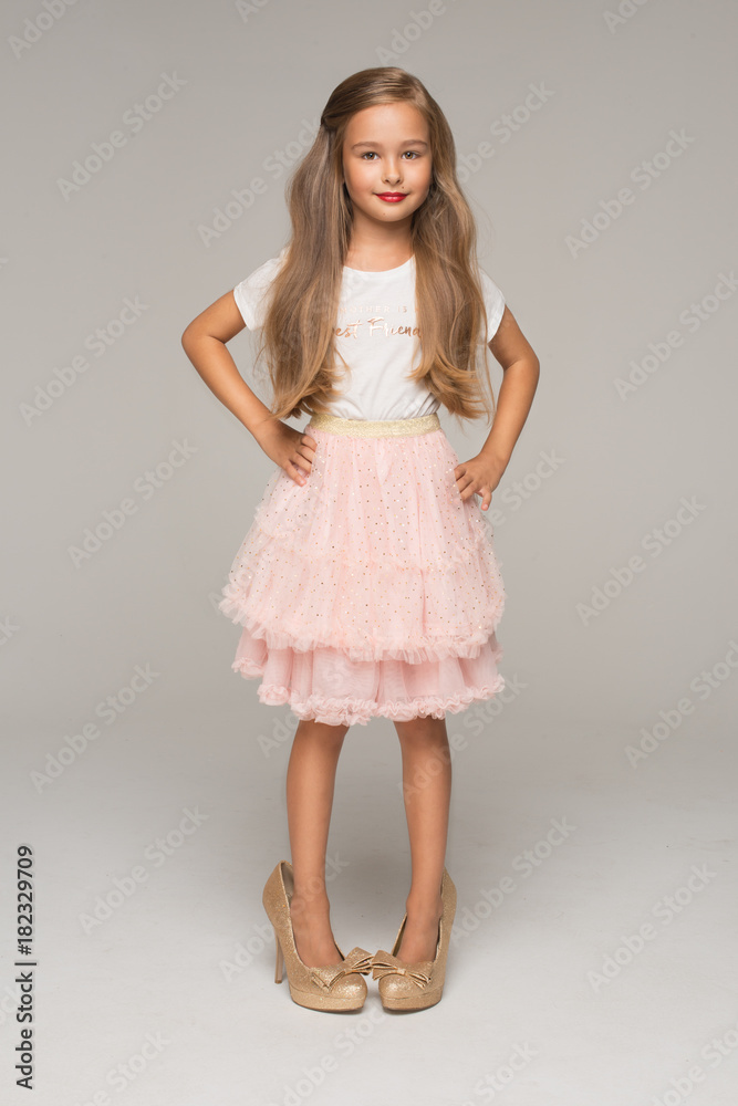 Cute little girl in pink tulle skirt and too big shoes