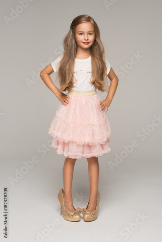 Cute little girl in pink tulle skirt and too big shoes