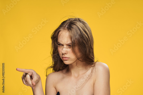 Young beautiful woman on a yellow background shows a blank space  portrait