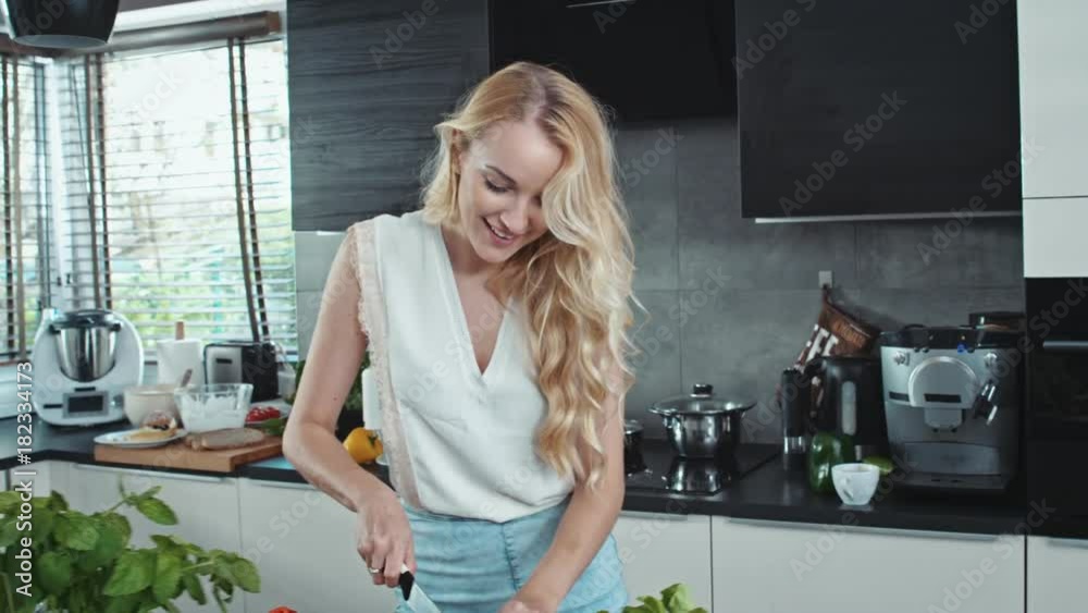 Charming blonde cooking in the cosy, bright kitchen Charming blonde cooking in the cosy, bright kitchen