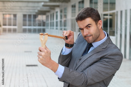 Competitive businessman using a slingshot photo