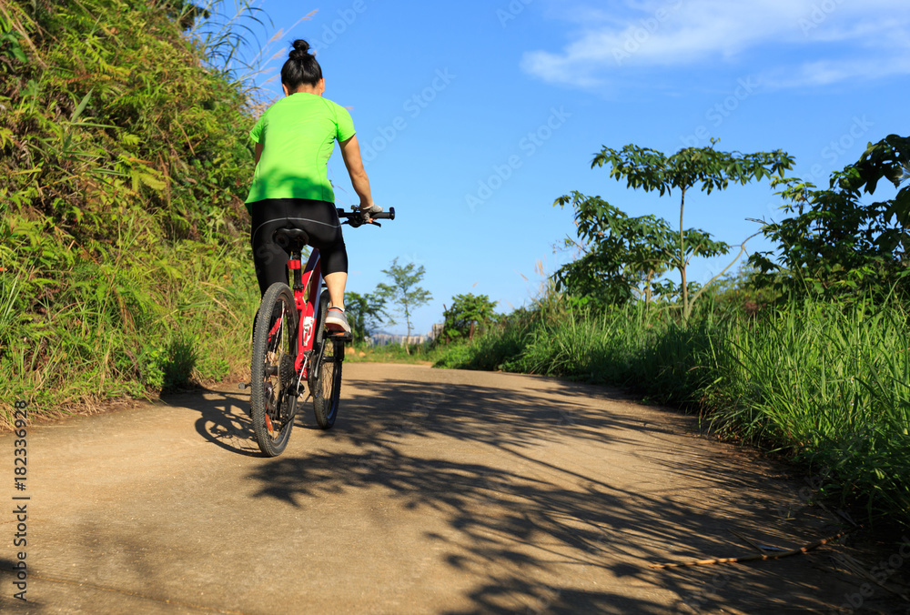 female cyclist riding mountain bike on country road