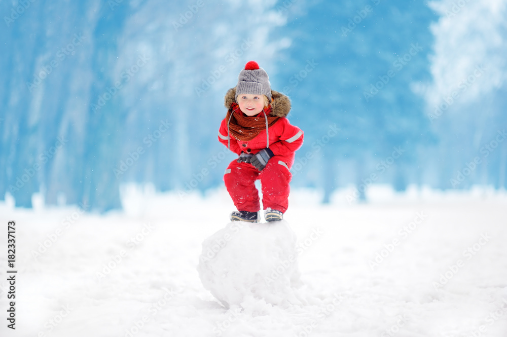 Little boy in red winter clothes having fun with snowball Little boy in red winter clothes having fun with snowball
