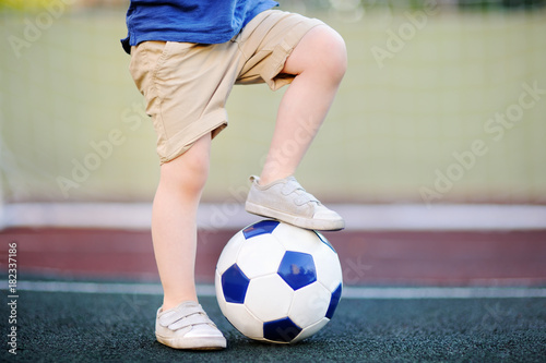 Little boy having fun playing a soccer/football game on summer day