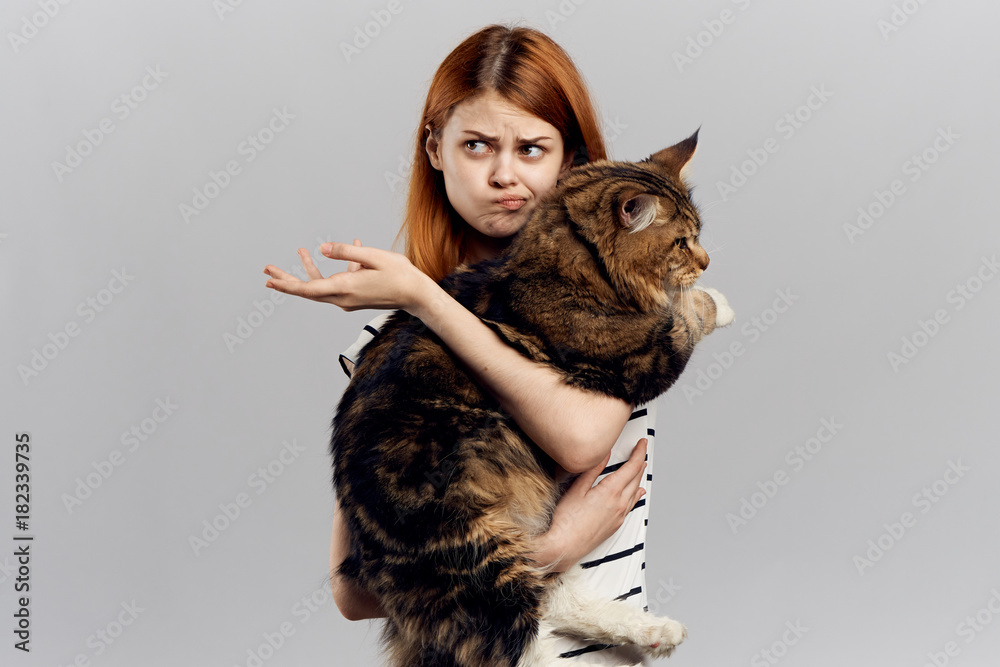 Young beautiful woman on a gray background holds a cat, emotions, pets