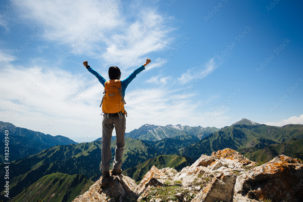 Successful woman backpacker enjoy the view on top of mountain rock Successful woman backpacker enjoy the view on top of mountain rock