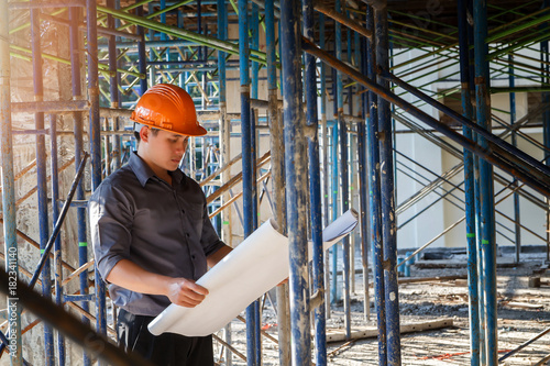 Engineer with blueprint in building construction site