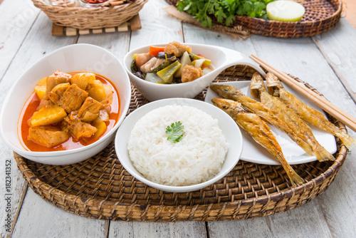 Massaman pork curry,  Chinese vegetable stew, Sand frying fish deep fried and steamed rice on wood background.