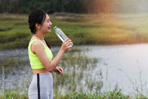 Attractive healthy fitness girl drinking water after workout. Runner girl take a rest after training.