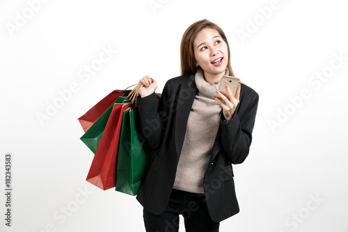 Woman holds a shopping paper bag and is happy watching a mobile phone.on white background