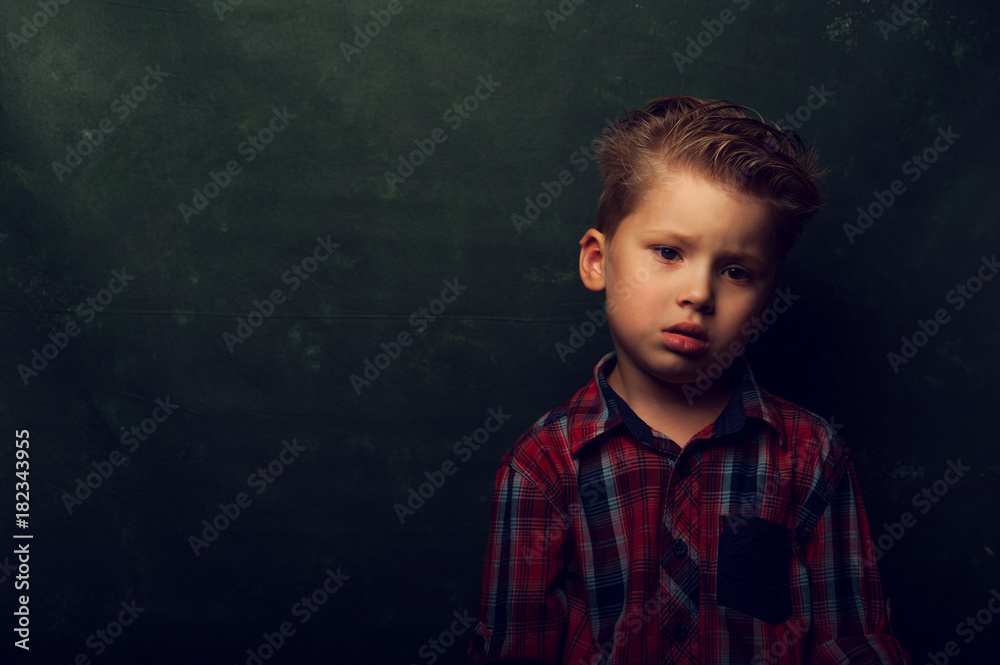 Sad displeased little boy stands in dark corner Sad displeased little boy stands in dark corner
