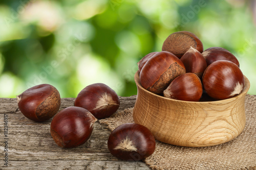 chestnut in bowl on the old wooden table with blurred garden background