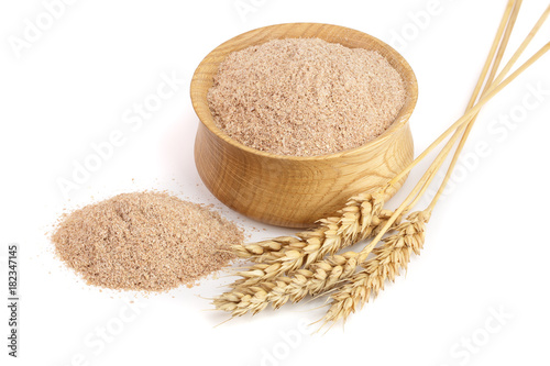Pile of wheat bran in wooden bowl with ears isolated on white background