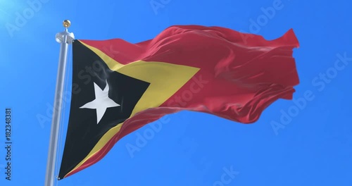 East Timorese flag waving at wind with blue sky in slow, loop photo